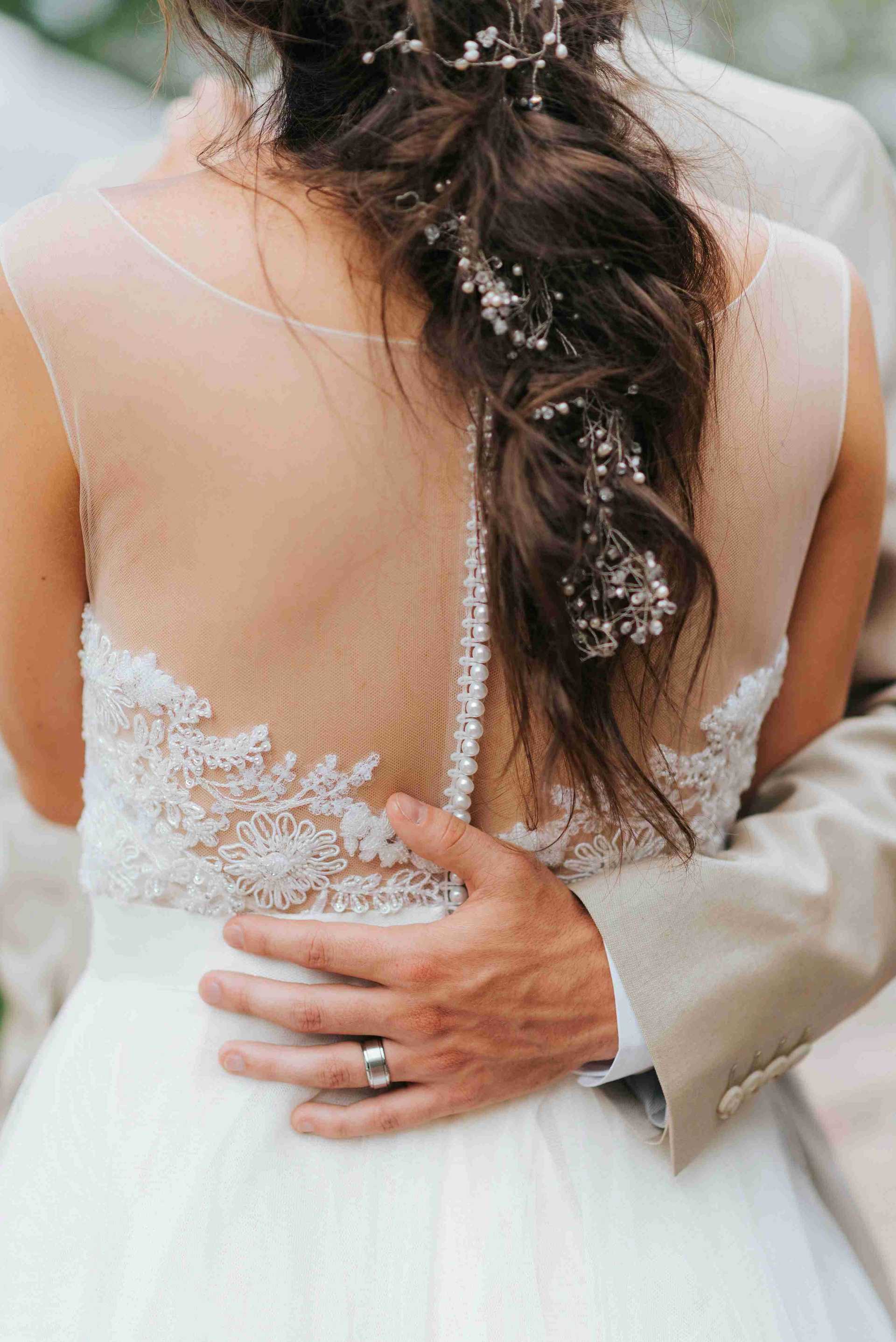 A bride wearing a wedding dress with lace details and a hair accessory.