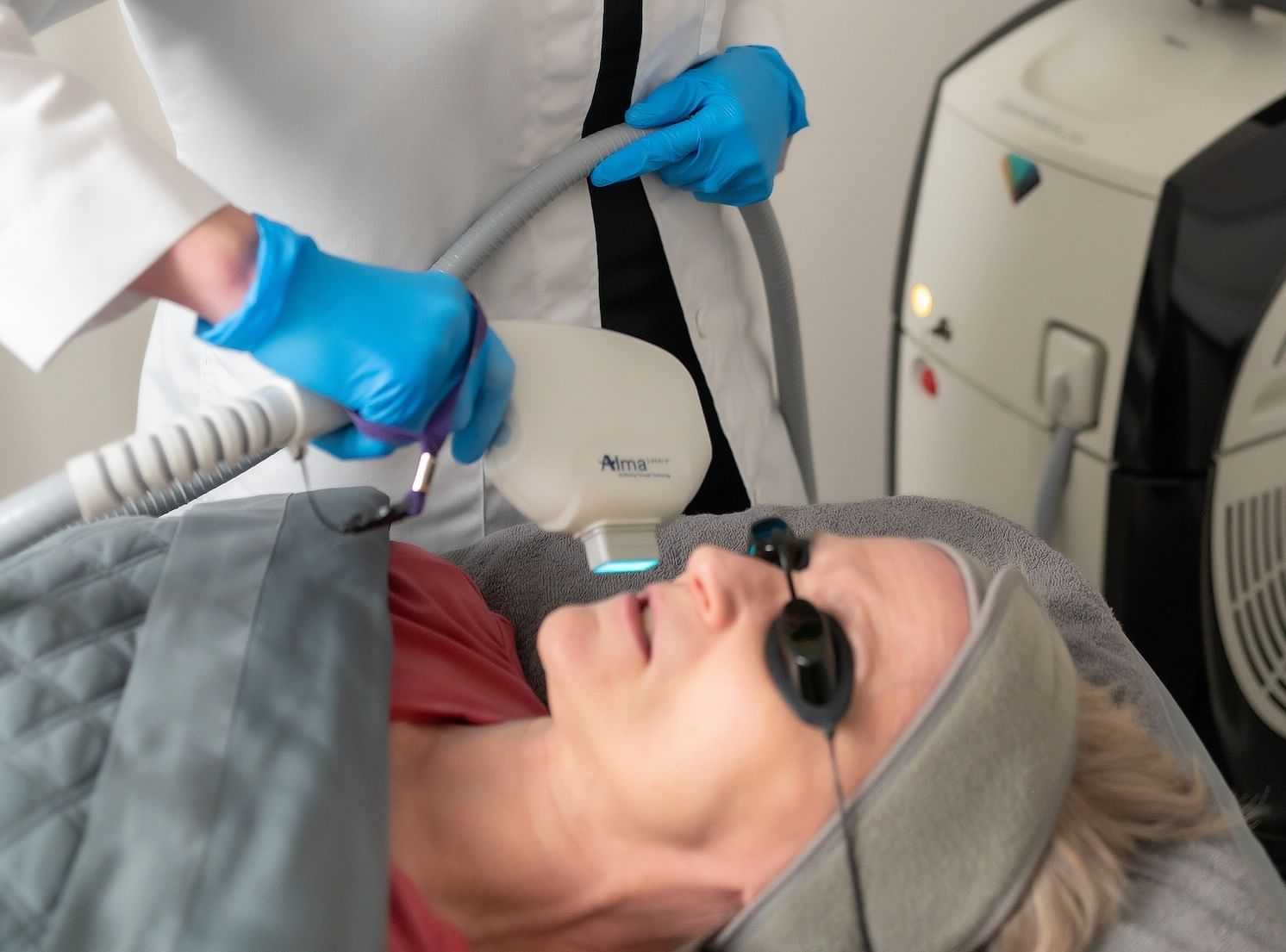 Woman receiving a facial laser treatment from a technician.